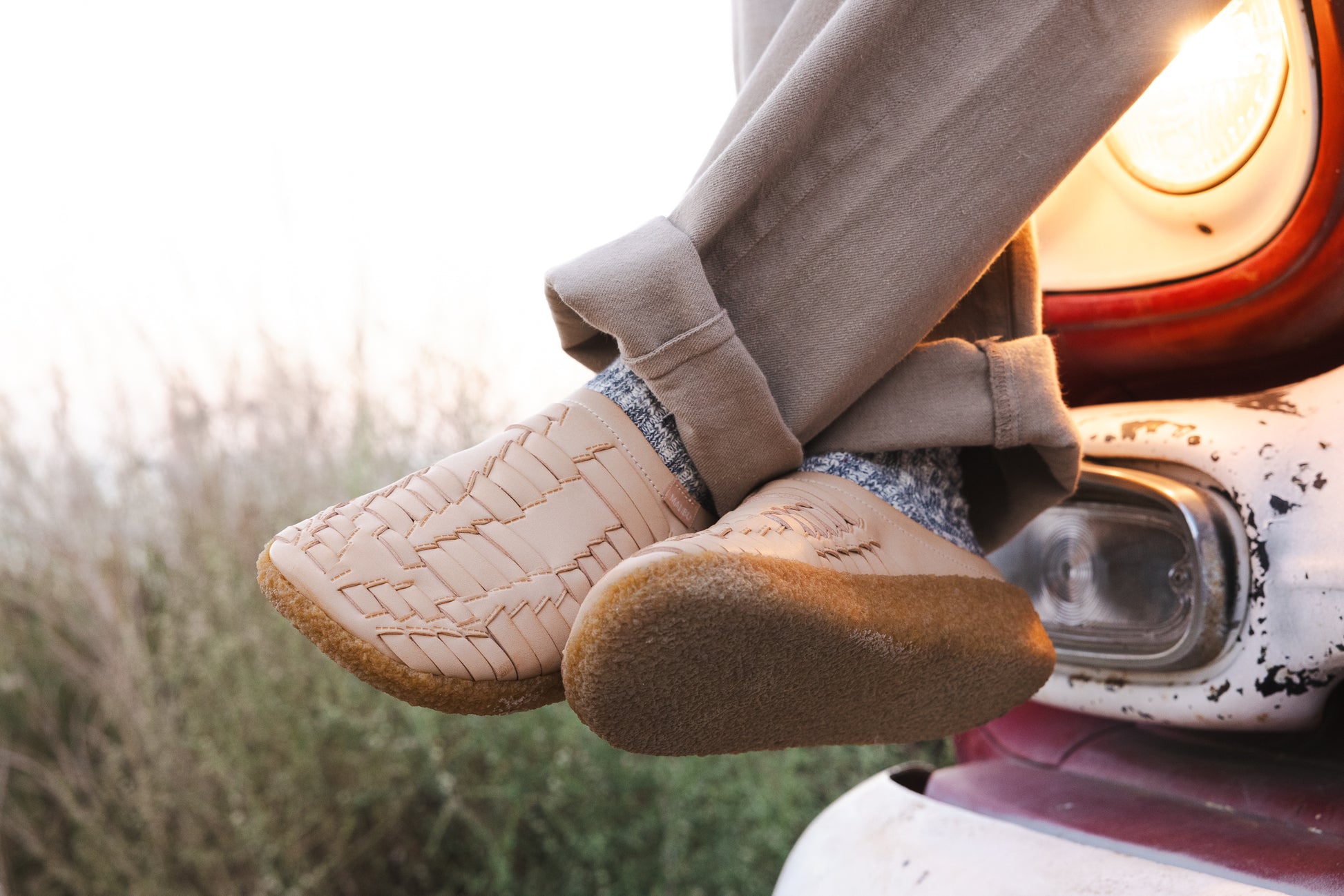 Malibu sandals all new thunderbird clog in vegan leather and crepe sole being worn with whole socks brown pants with the background of tall grass and headlight of the front bumper of a vintage truck